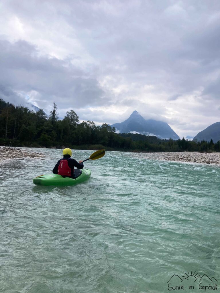 Kajak auf dem blauen Fluss, im Hintergrund Berge.